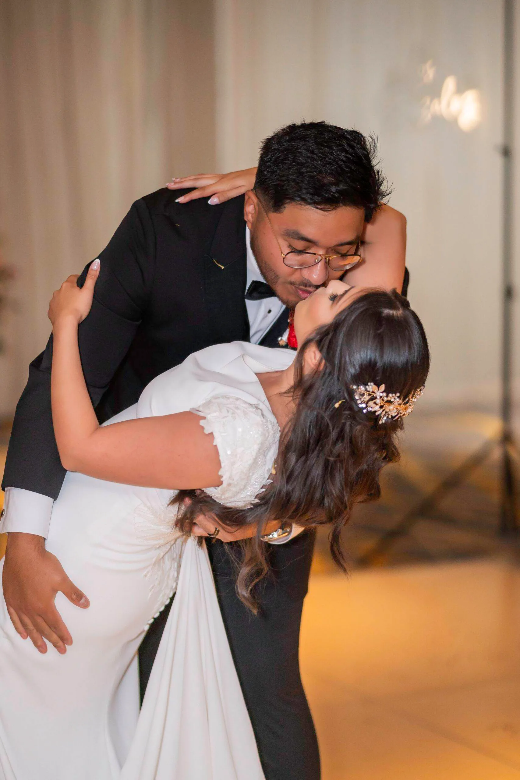 A groom dipping a smiling bride indoors.