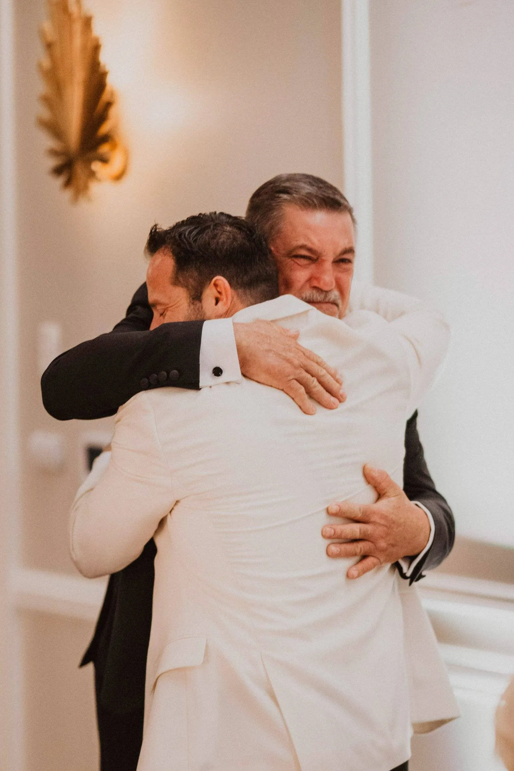 Two men sharing an embrace at a wedding.
