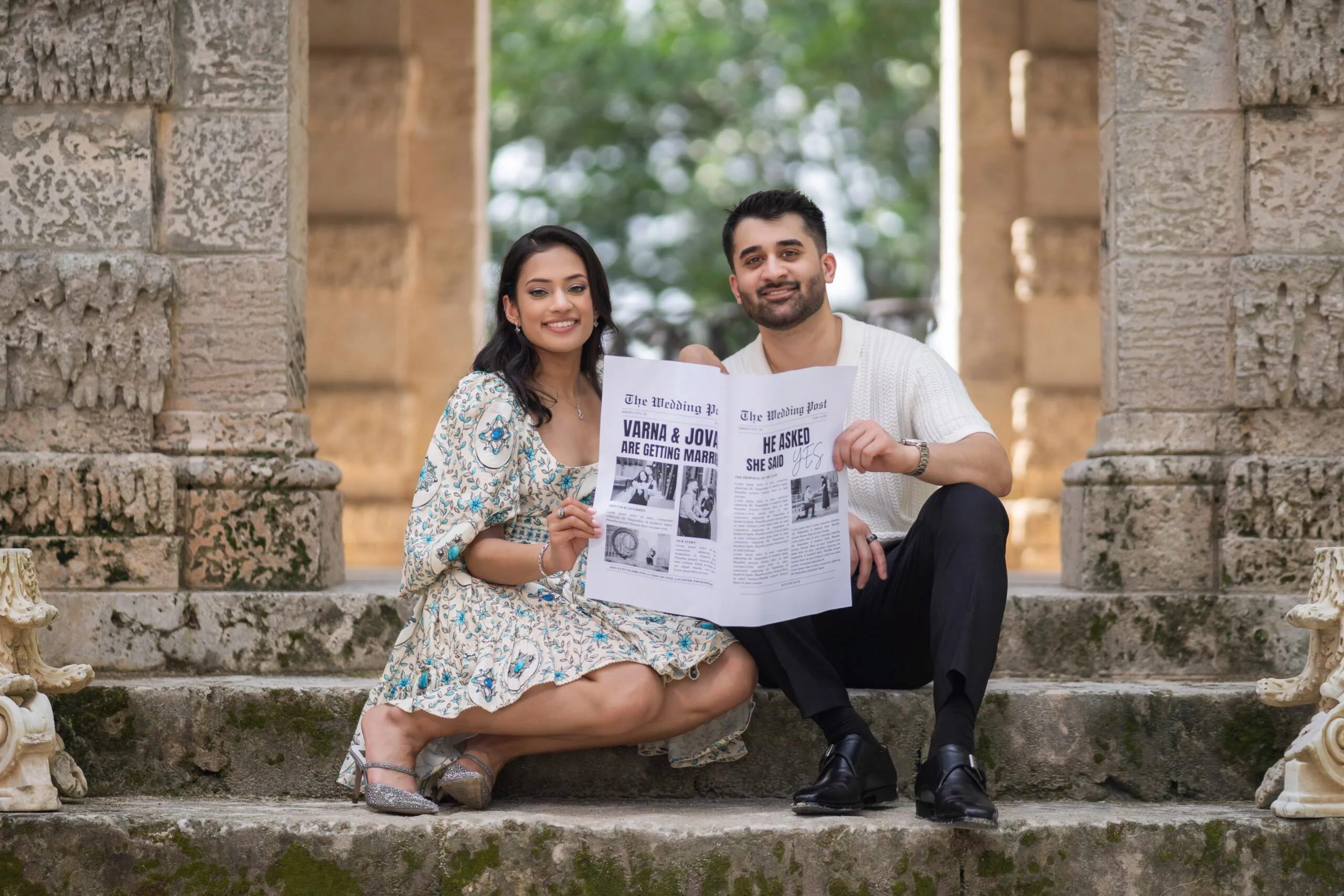 A seated couple holding a personalized newspaper during an outdoor portrait session.