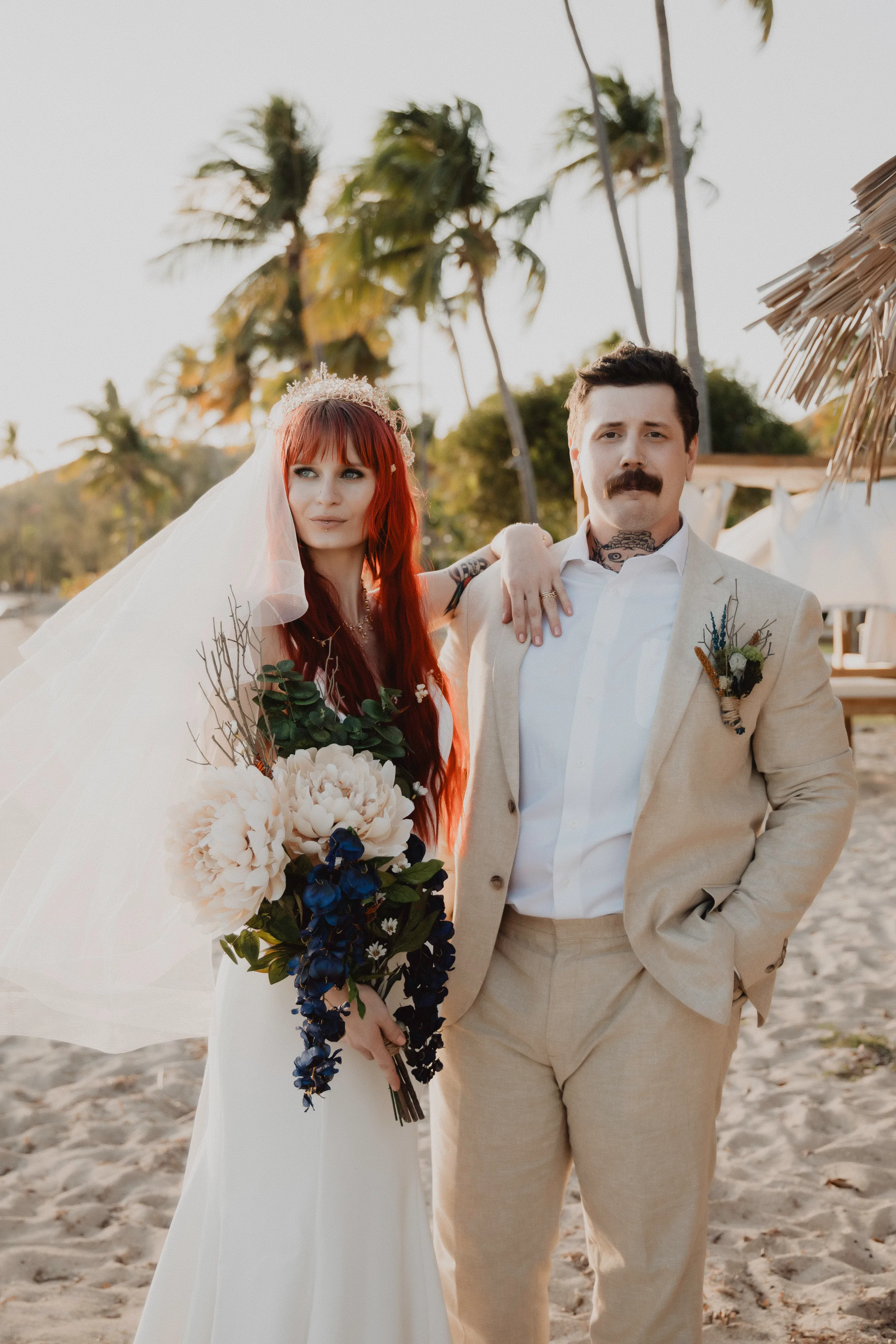 A bride and groom standing together on a beach.