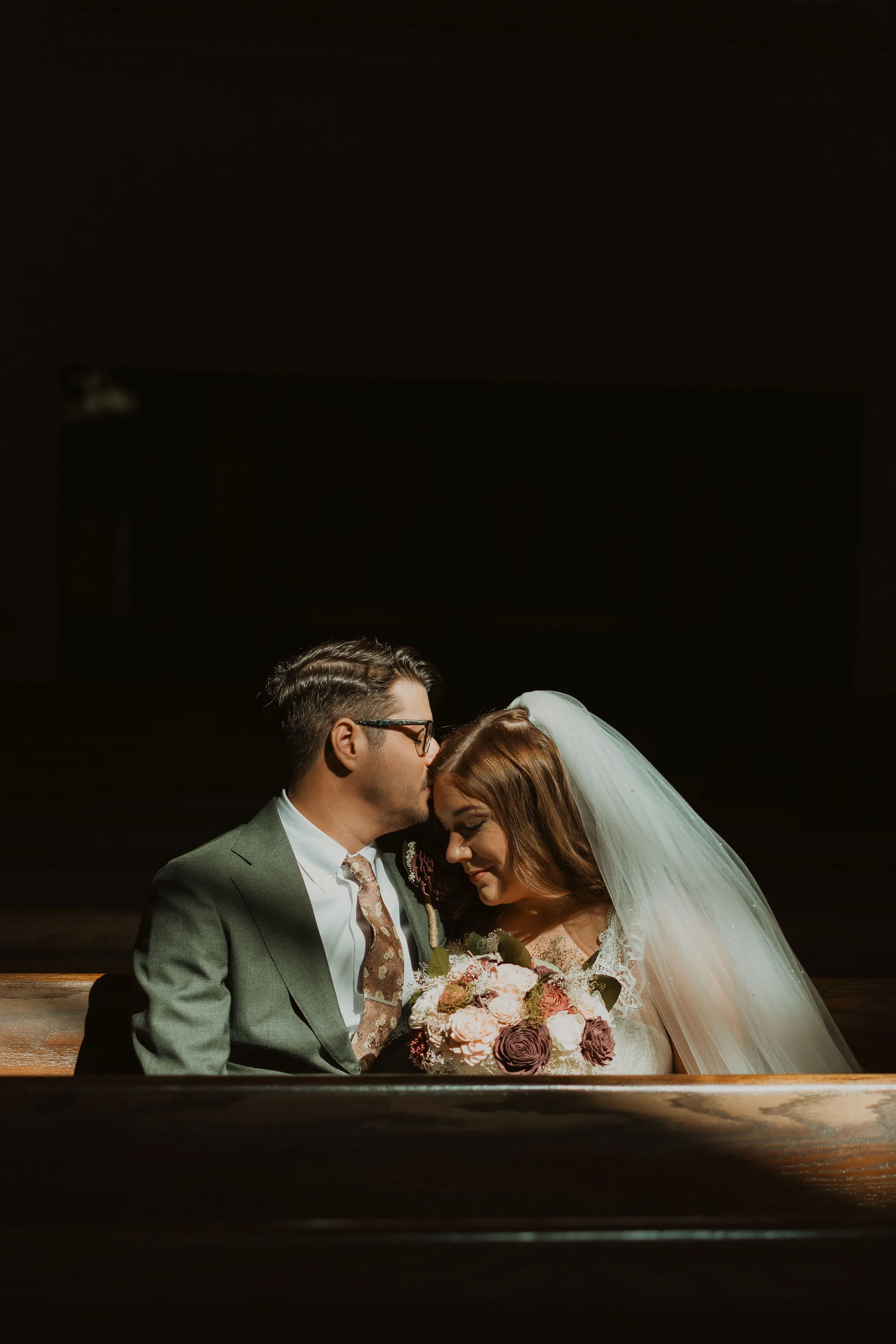 A bride and groom walking hand in hand in a beautiful garden on their wedding day. A tender moment between a bride and groom in a dimly lit church pew, bathed in soft golden light.