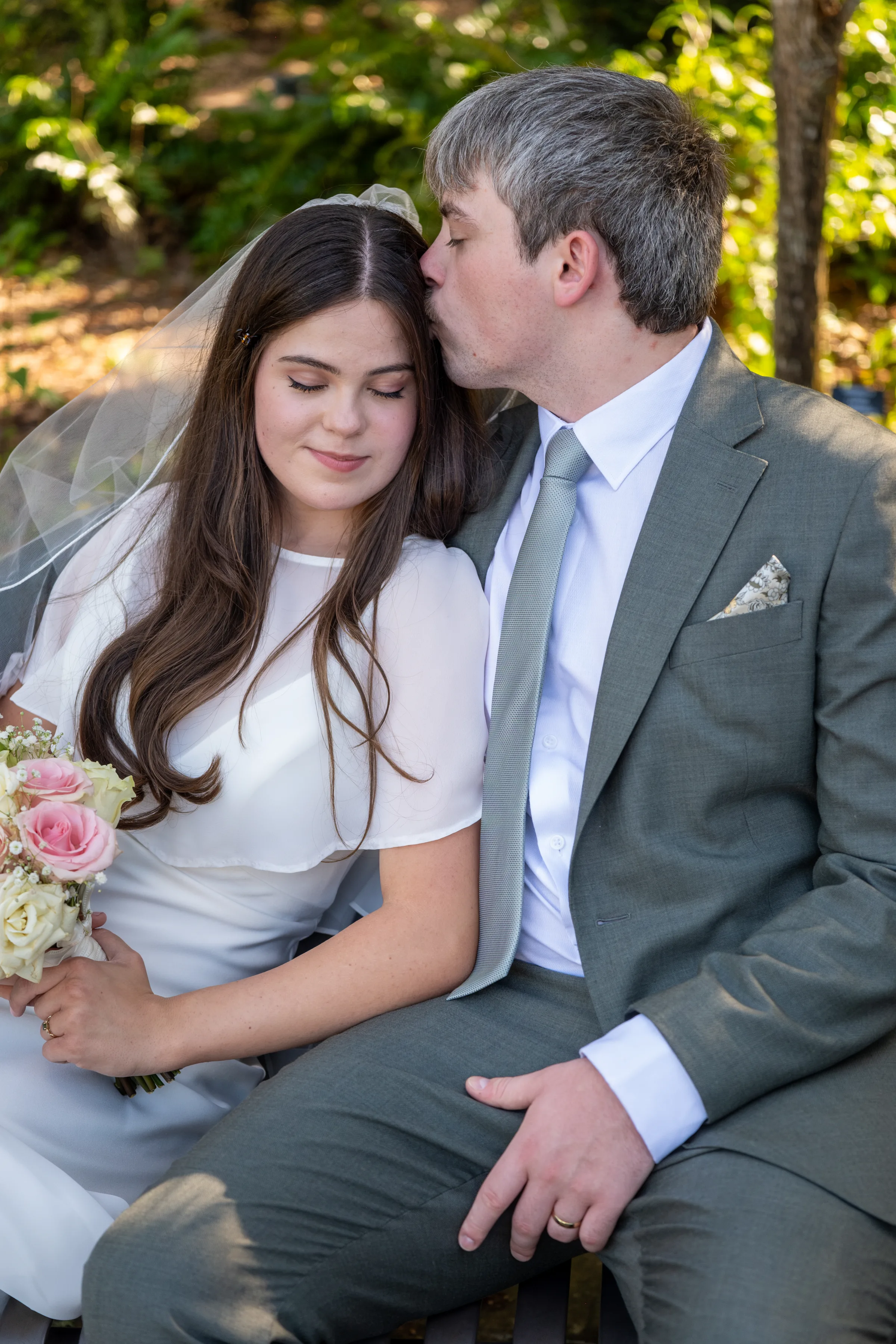 A groom kissing a bride on the forehead during a wedding portrait at Harry P. Leu Gardens.