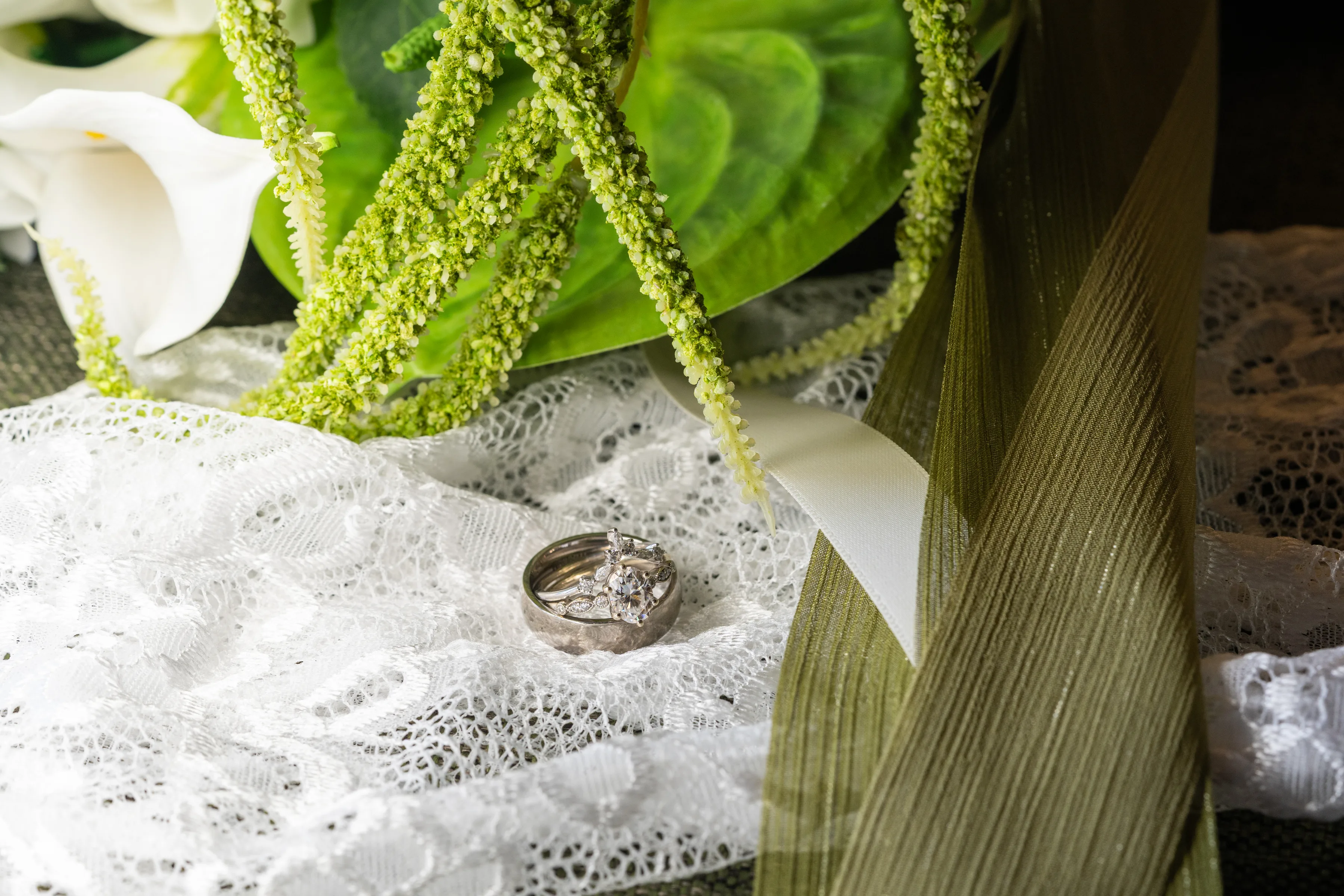 Wedding rings photographed with lace and white flowers.