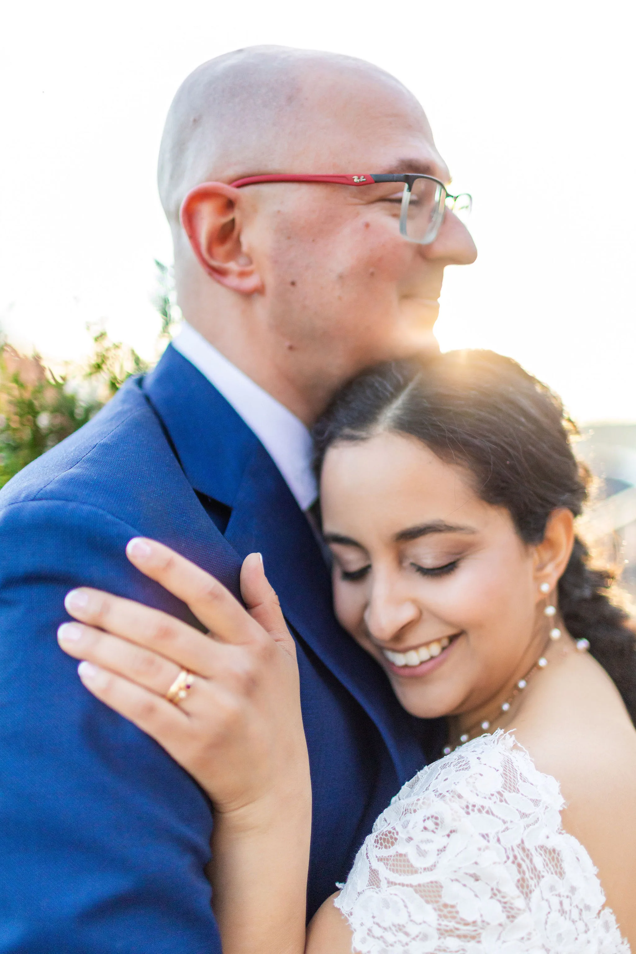 photographer directing couple golden hour - golden hour wedding photos A bride and groom share a tender embrace under the warm glow of golden hour sunlight.