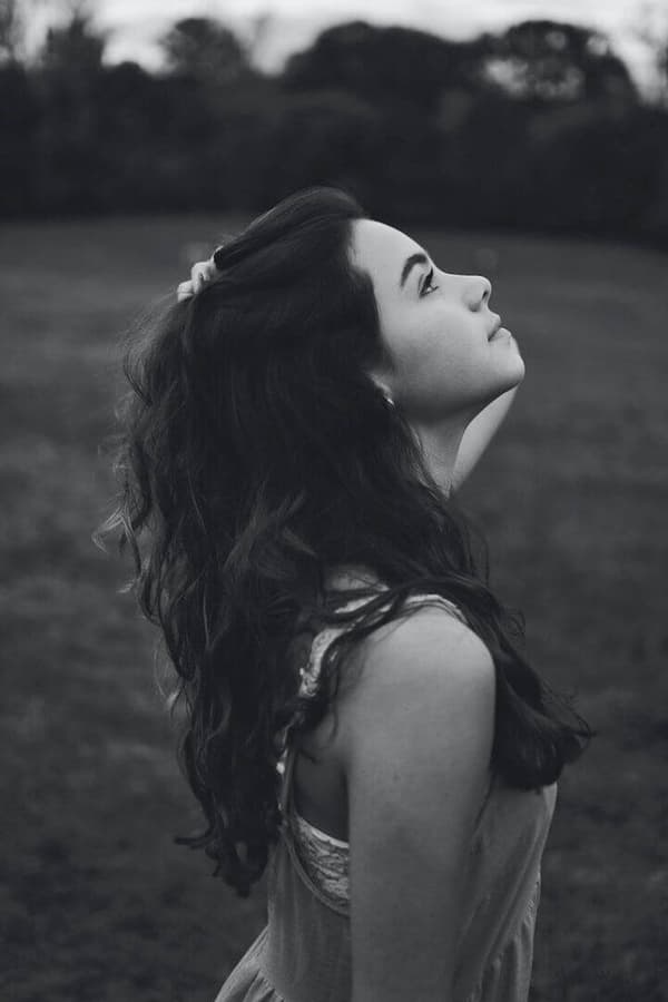 A woman with long dark hair is looking up at the sky.